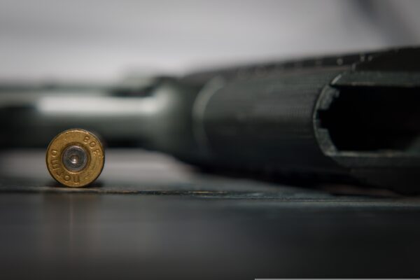 spłonka amunicji 9mm wraz z pistoletem w tle jako ilustracja pozwolenia na broń